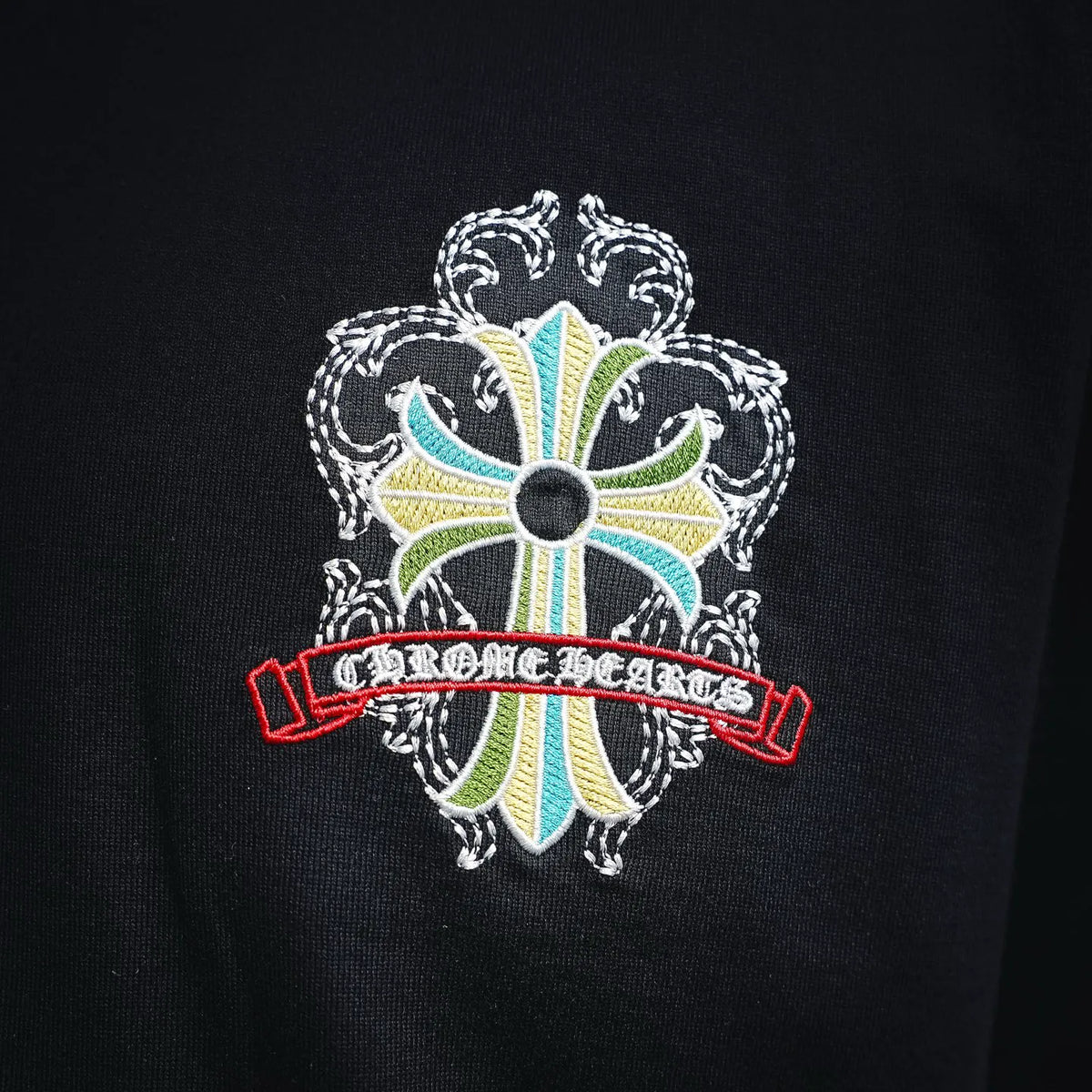 Black T-shirt close-up of embroidered floral cross chest logo