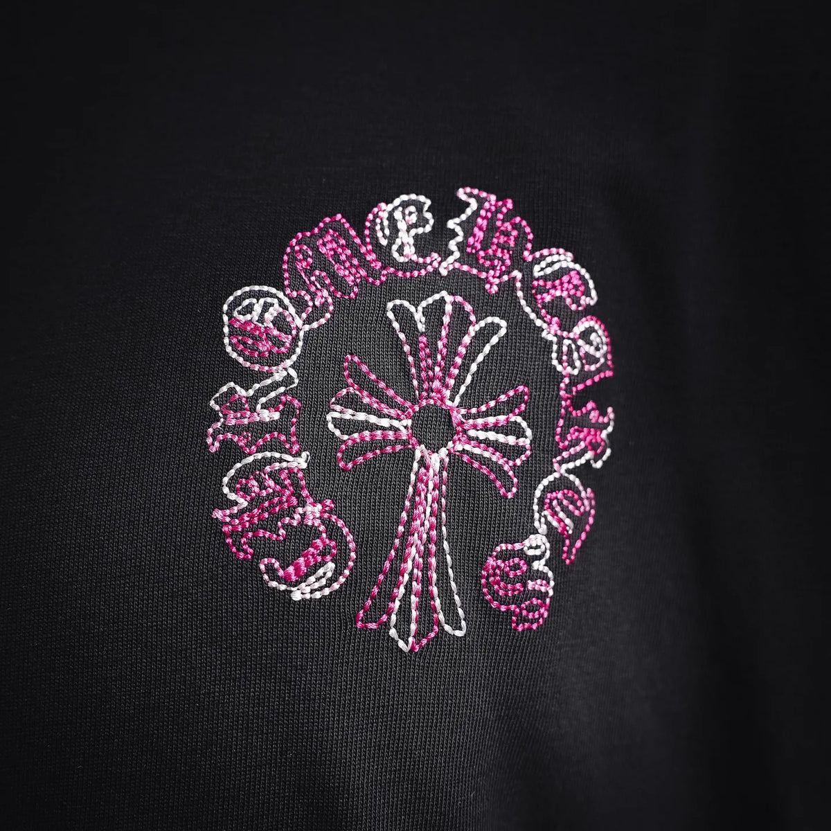 Black T-shirt close-up of pink-and-white circular chest graphic