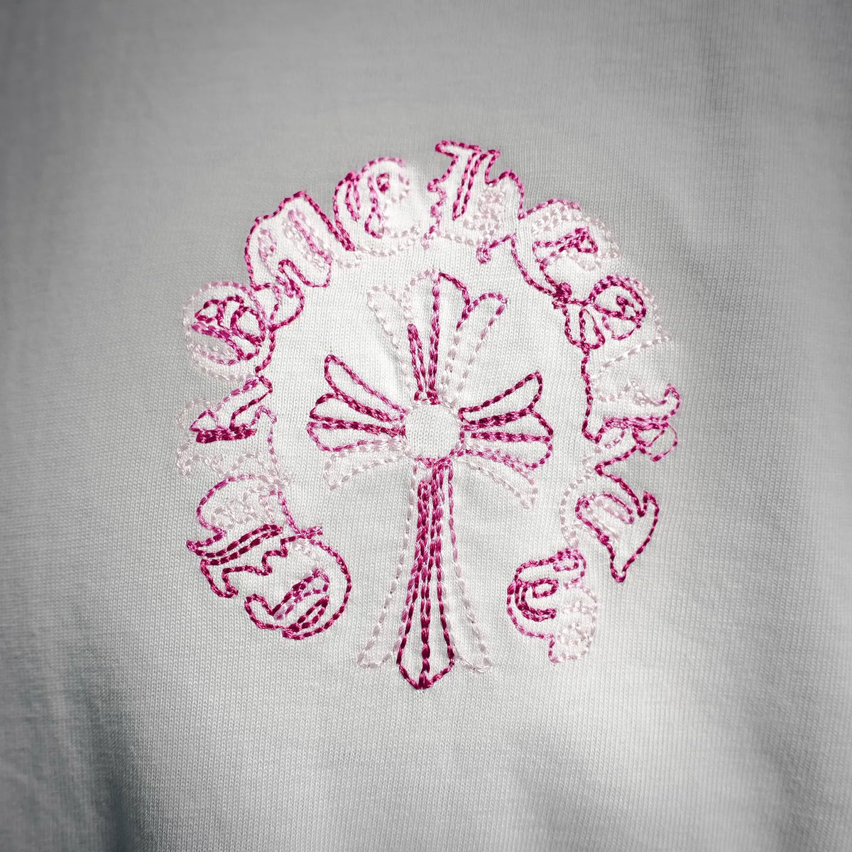 White T-shirt front with centered pink stitched flower motif
