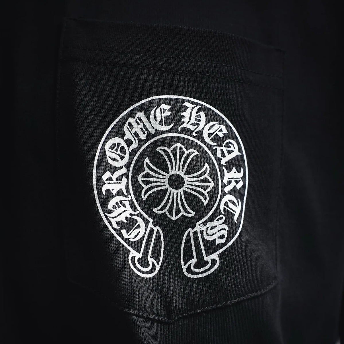 Men's black T-shirt pocket area with round white crest logo patch