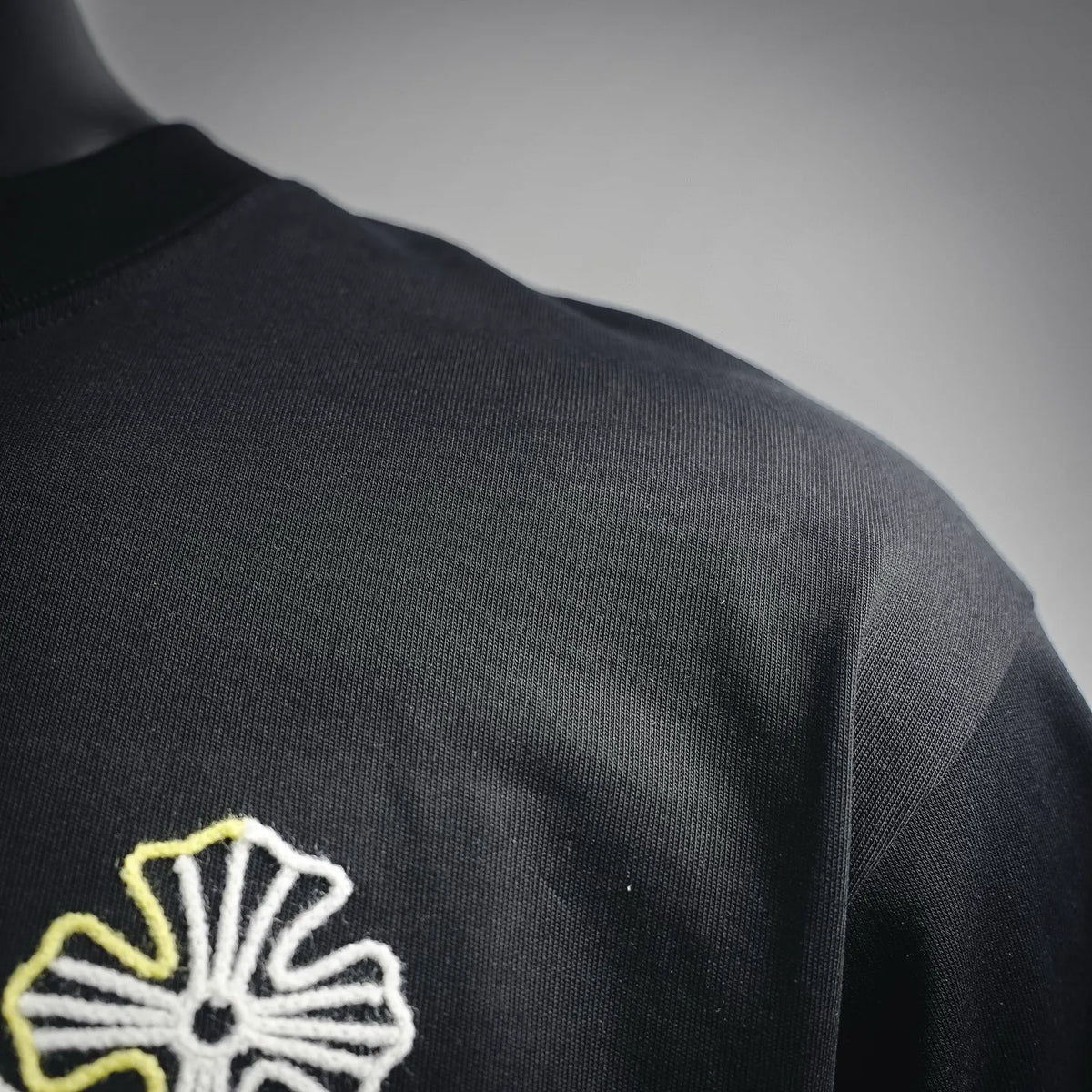 Close-up of multicolor embroidered flower patch on black T-shirt shoulder