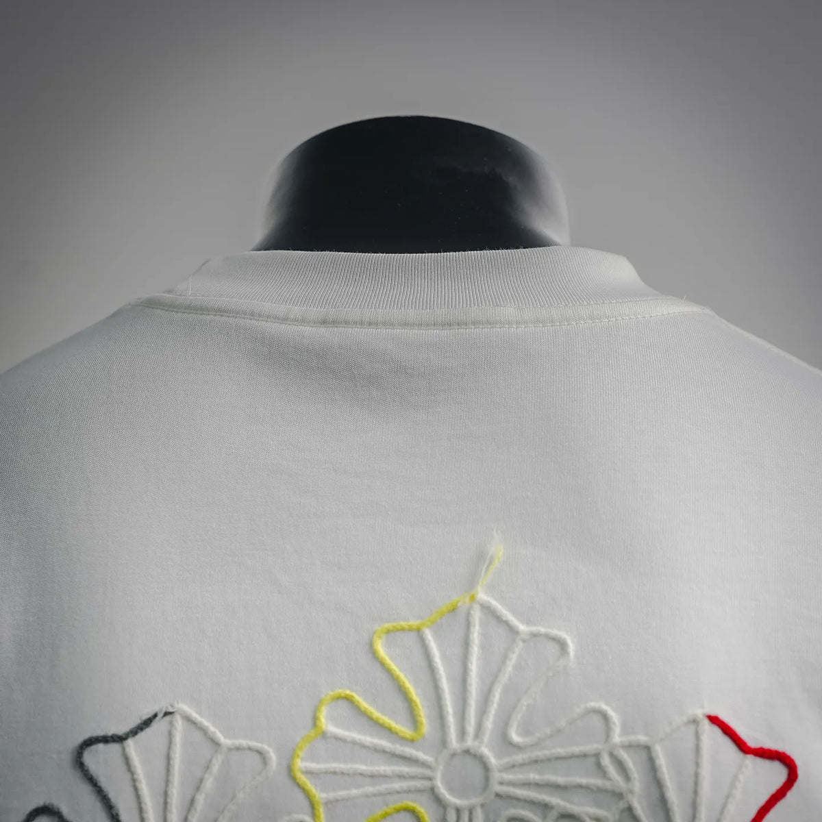 White crew-neck T-shirt back with embroidered multicolor graphic near the collar