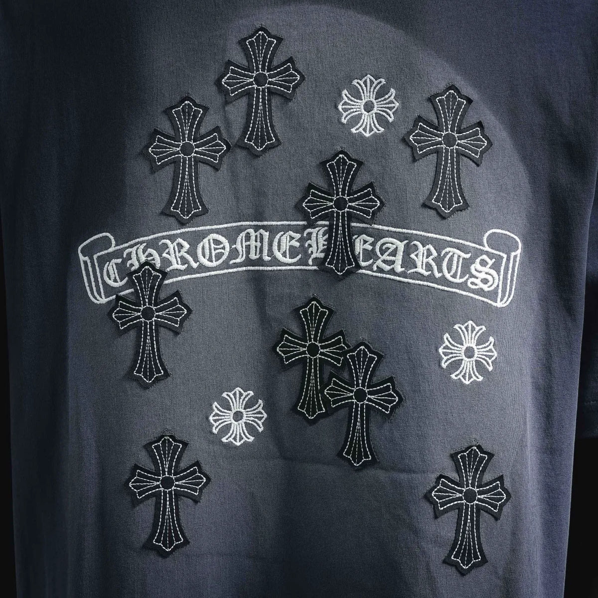 Blue t-shirt with ornate cross patchwork and arched text graphic
