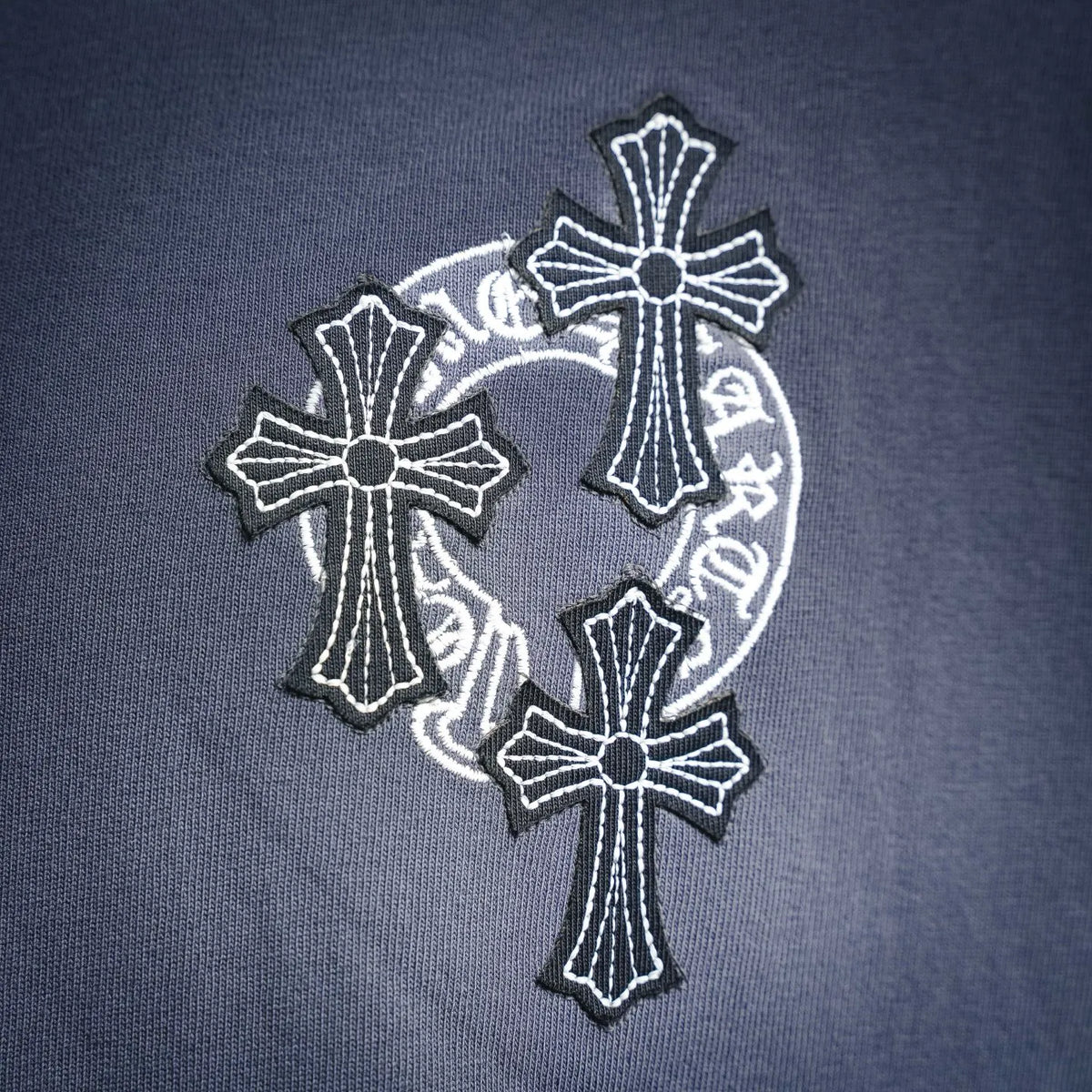 Blue t-shirt with large crest-style cross logo on the chest