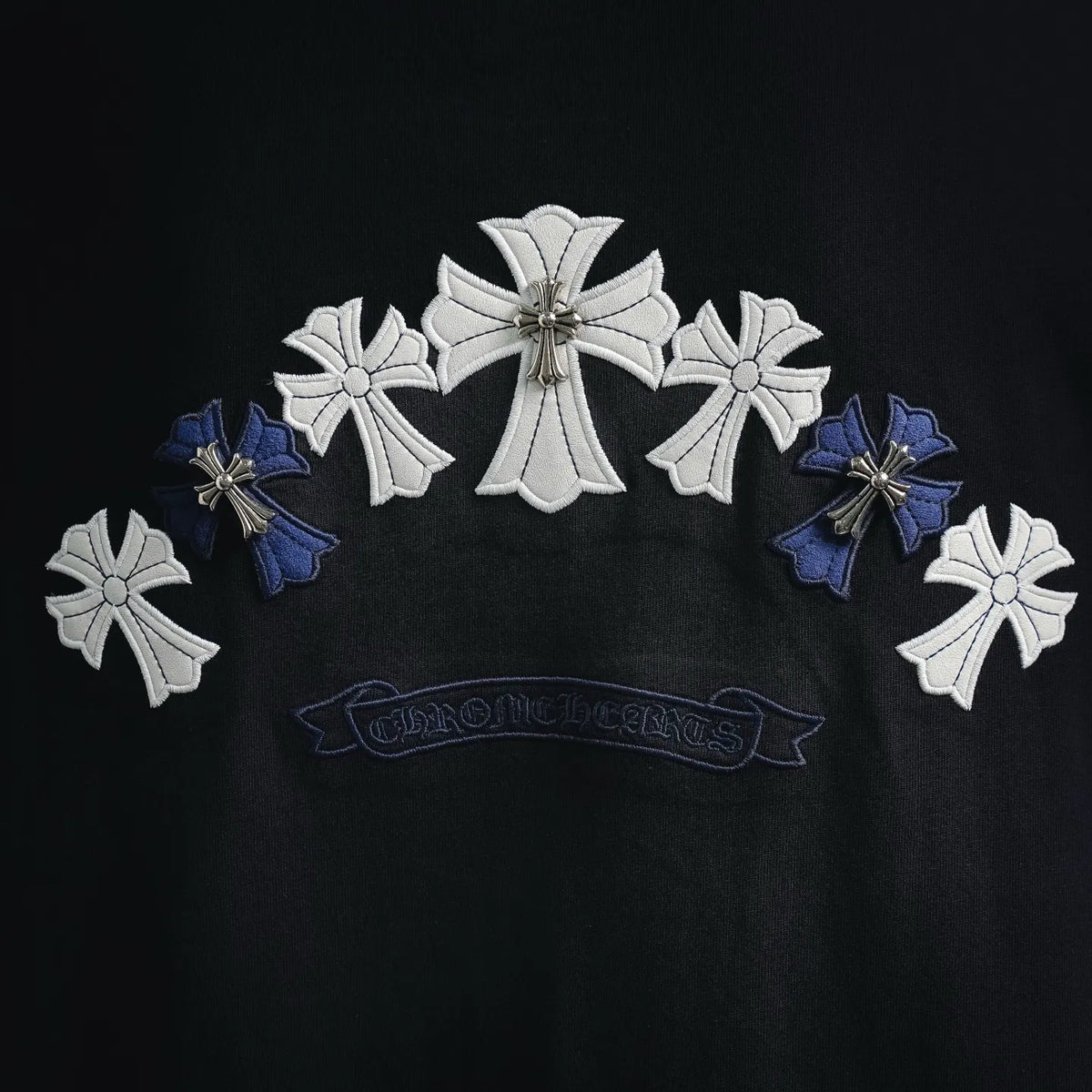 Black T-shirt with large white cross and blue petal-style embroidery graphic