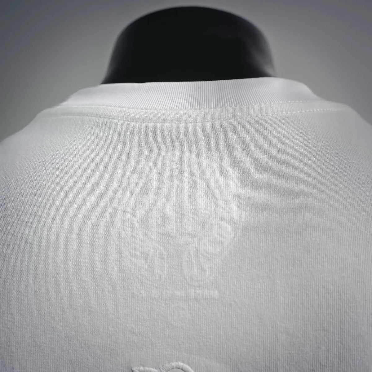 White T-shirt back neckline with subtle embossed-style emblem
