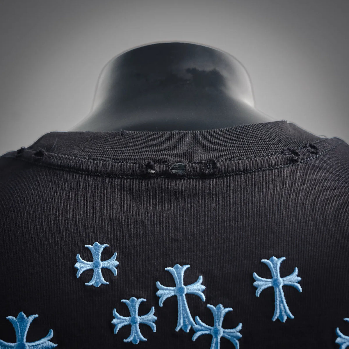 Black T-shirt neckline with blue snowflake embroidery detail on upper chest