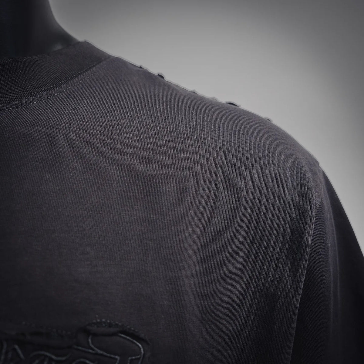 Black T-shirt back yoke with subtle stitching and worn blue graphic edge