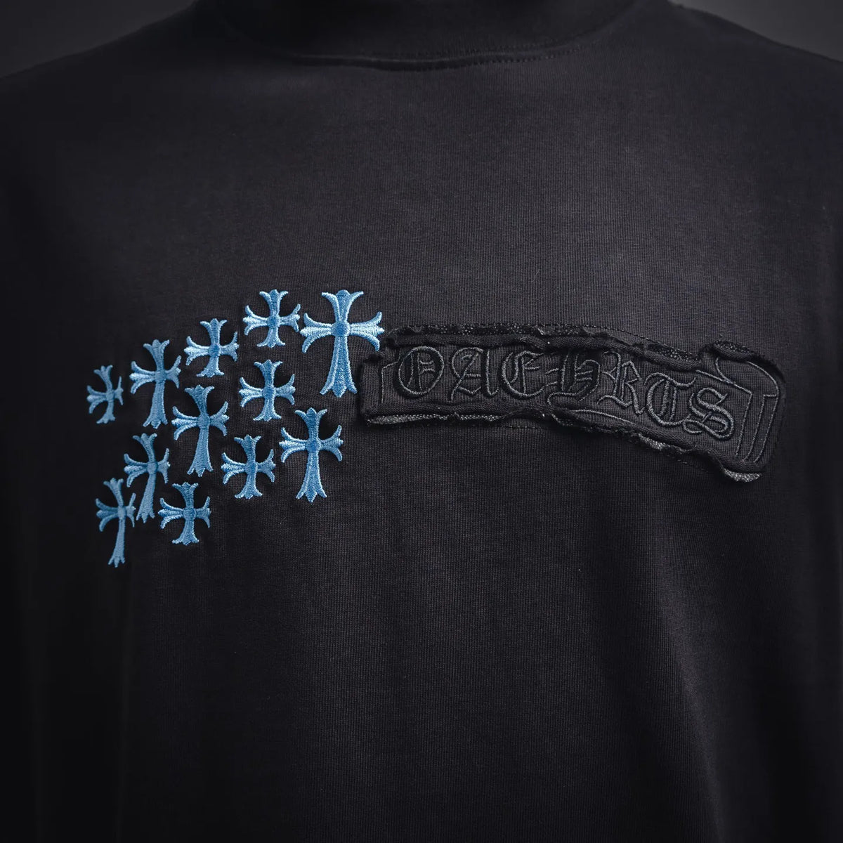 Black T-shirt chest area with blue snowflake cluster and dark logo patch