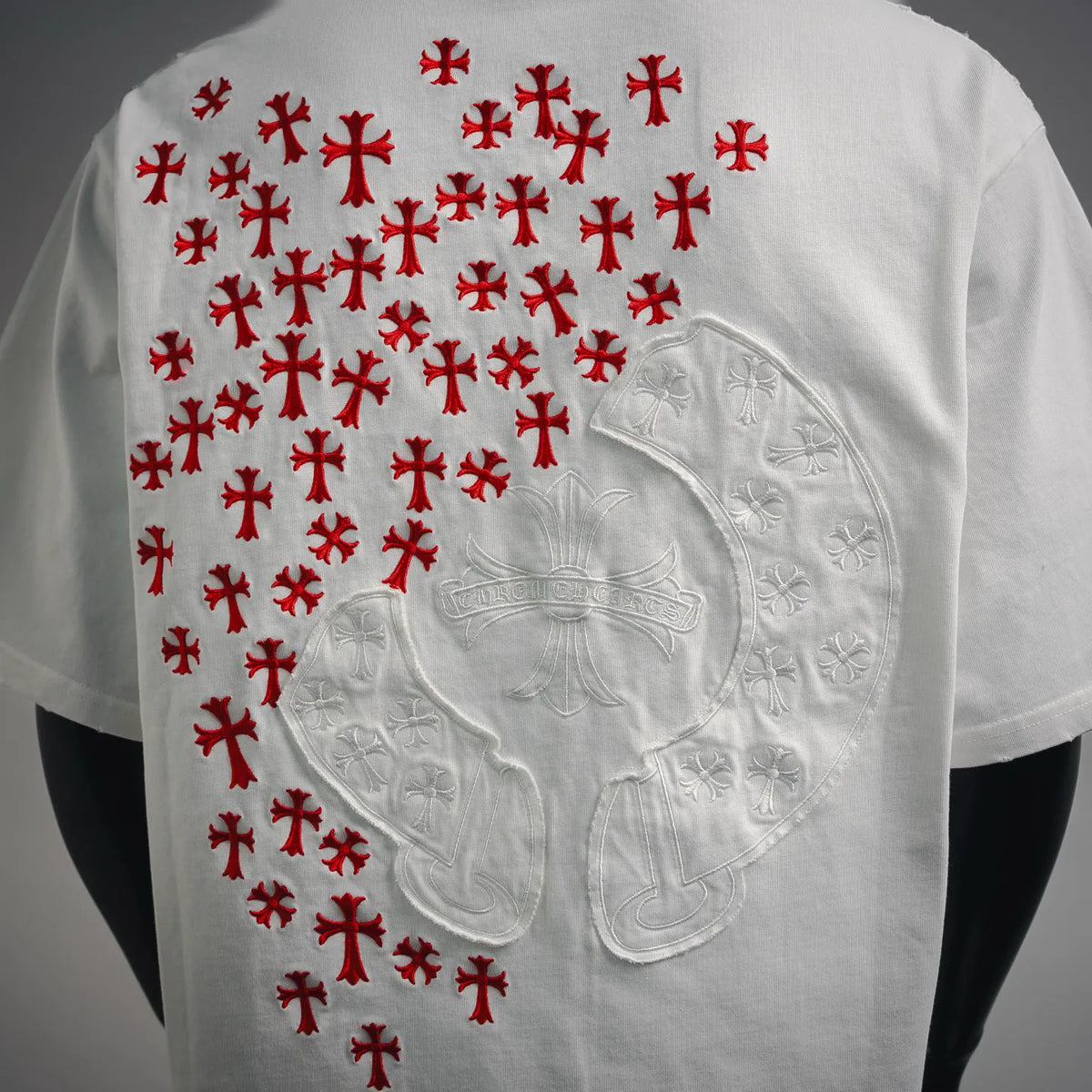 Back of white T-shirt close-up: red crosses over embossed white heart graphic
