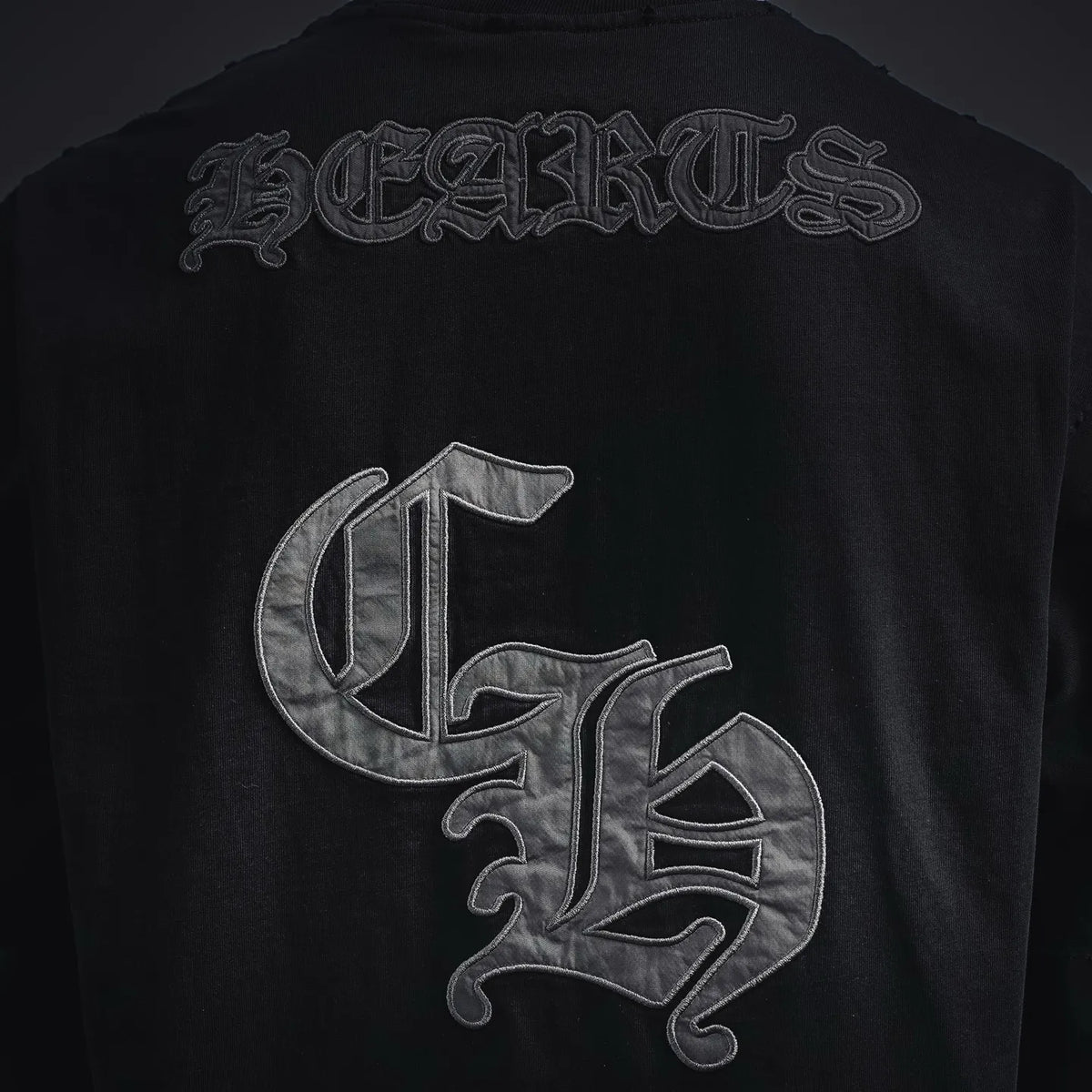Black crewneck T-shirt back graphic: large chrome-style letters and emblem