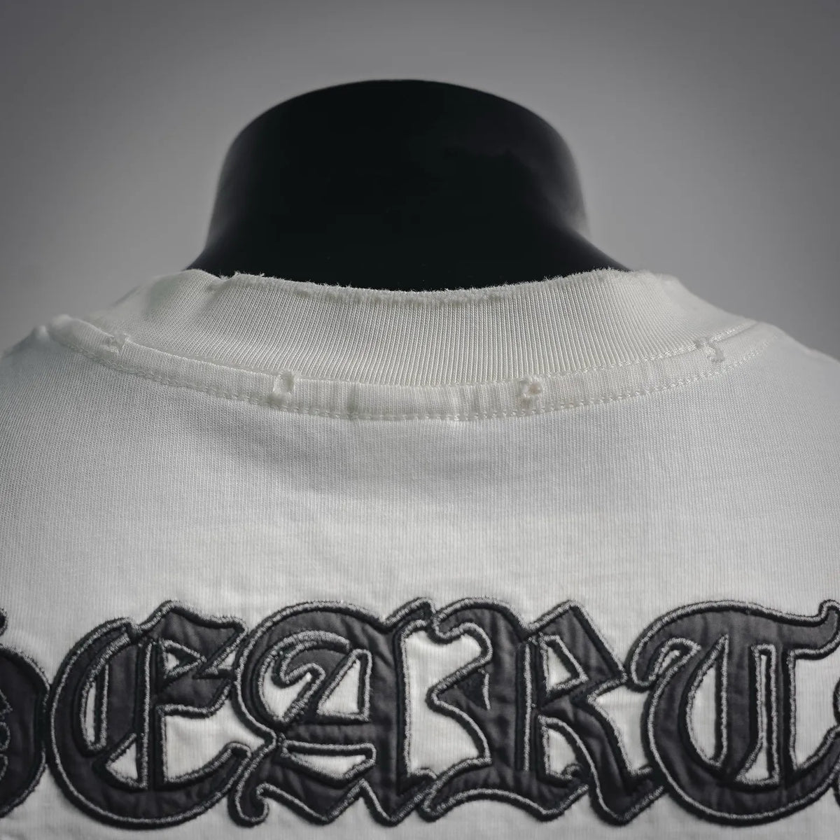 Close-up of white T-shirt collar with embroidered dark logo
