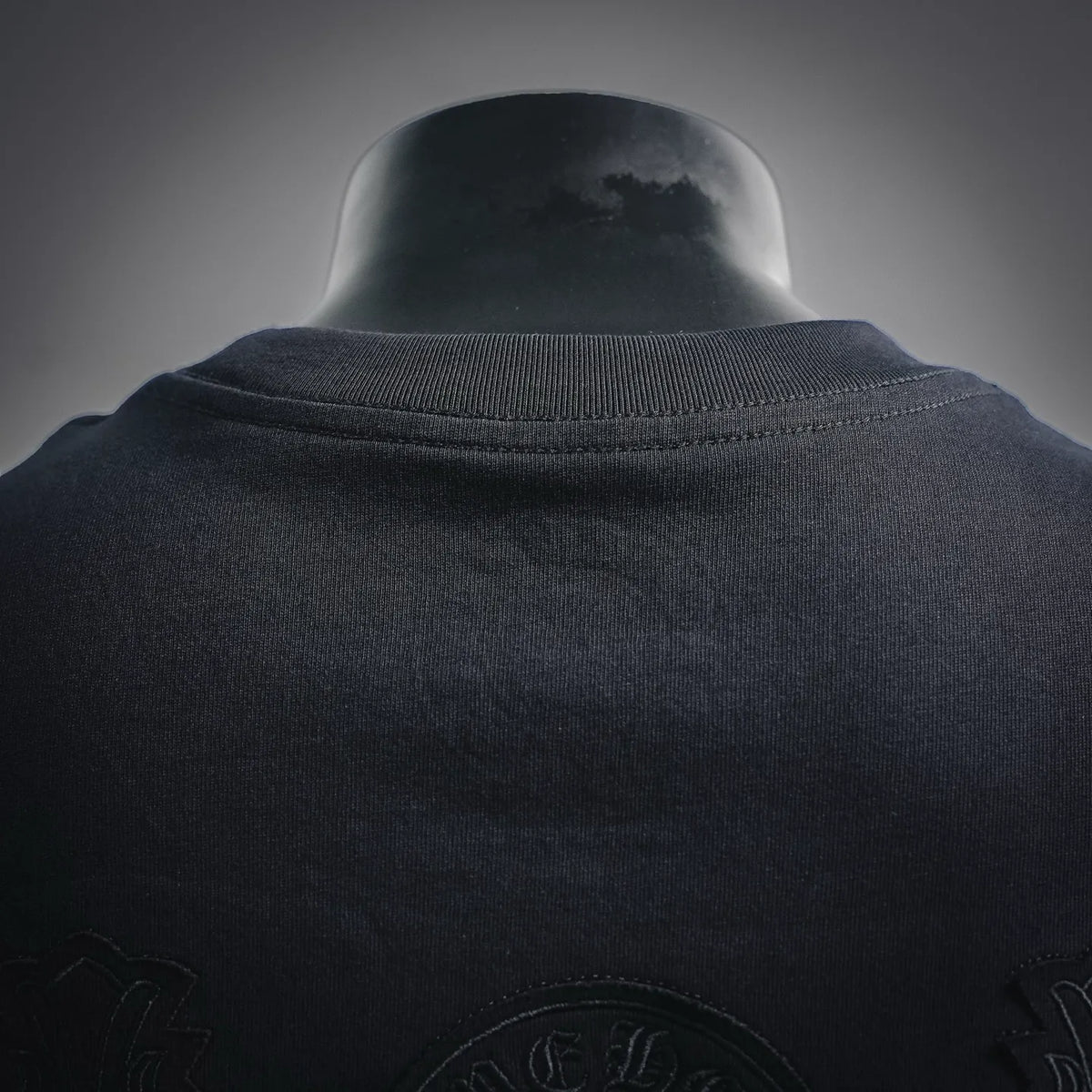 Black T-shirt collar with ribbed neckline; embossed back logo detail below