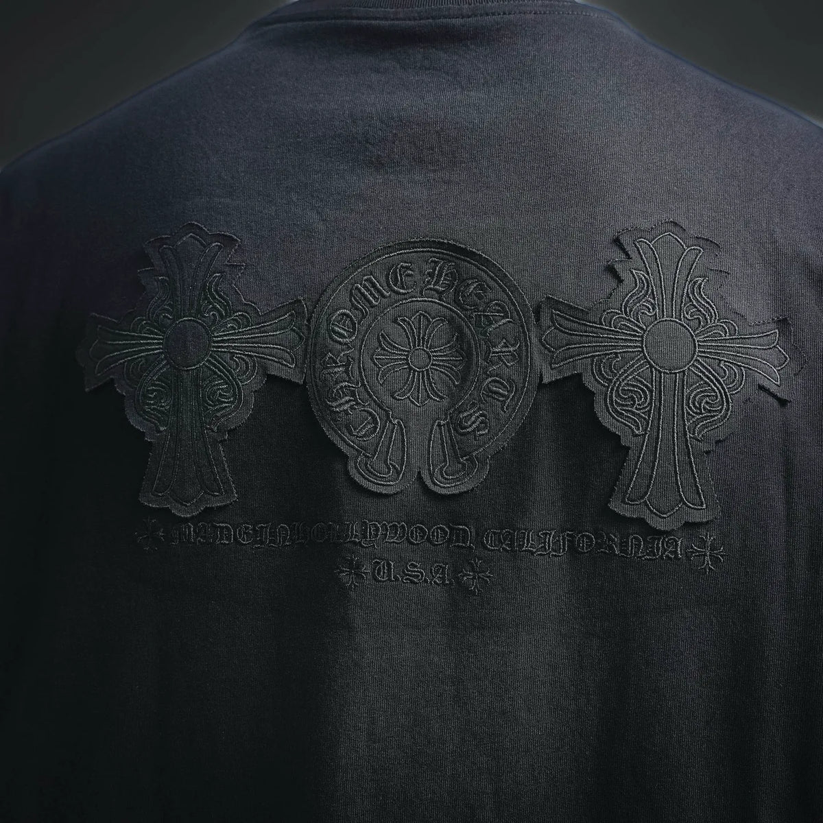 Black T-shirt back with large embossed cross center graphic and side emblems