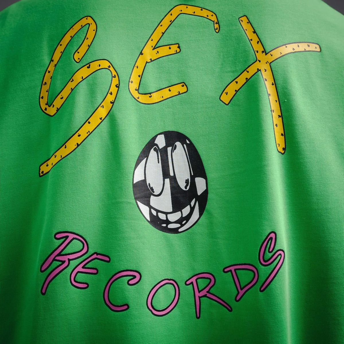 Green T-shirt with “Sex Records” script and black-and-white skull graphic