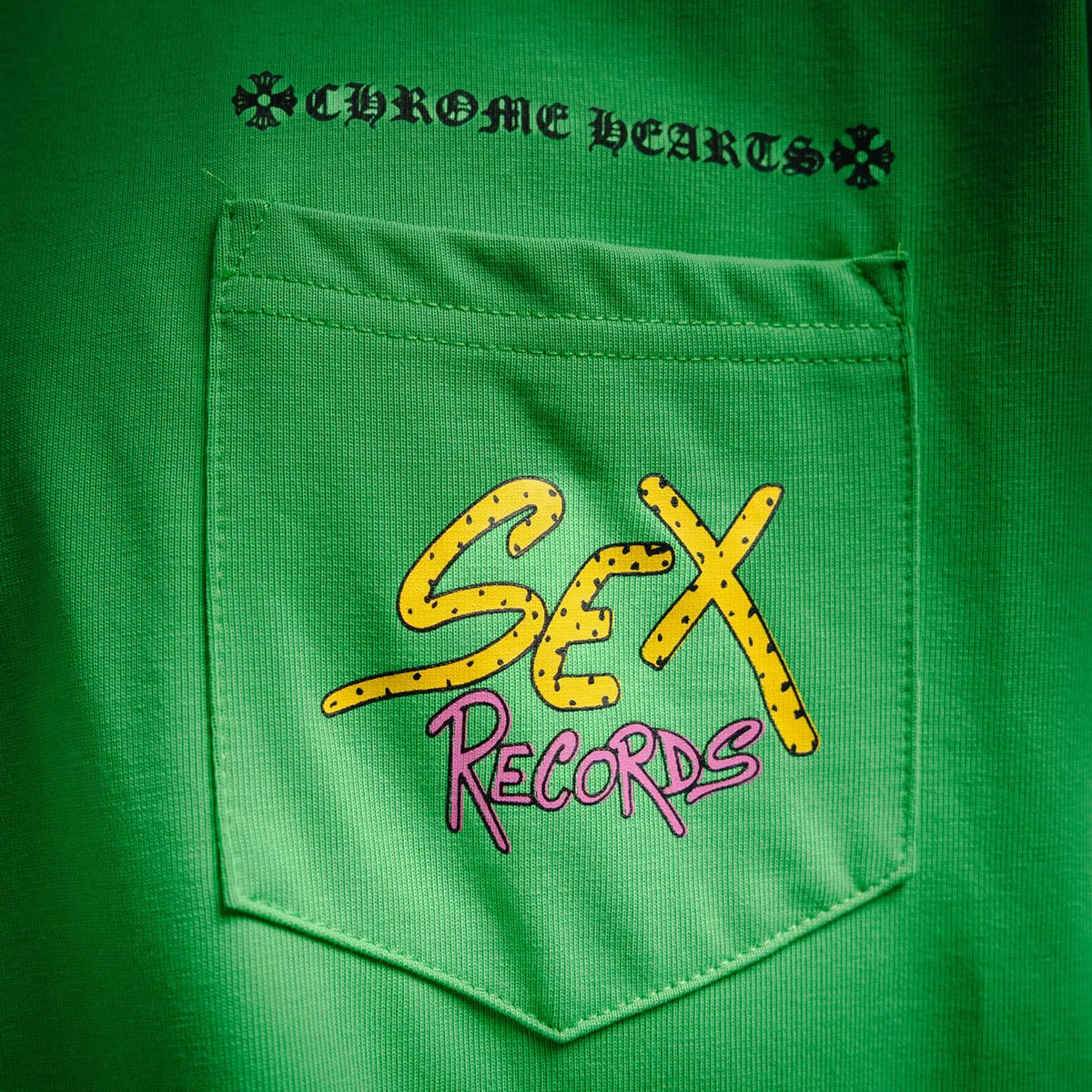 Green T-shirt front pocket with yellow “Sex” and “Records” graphic