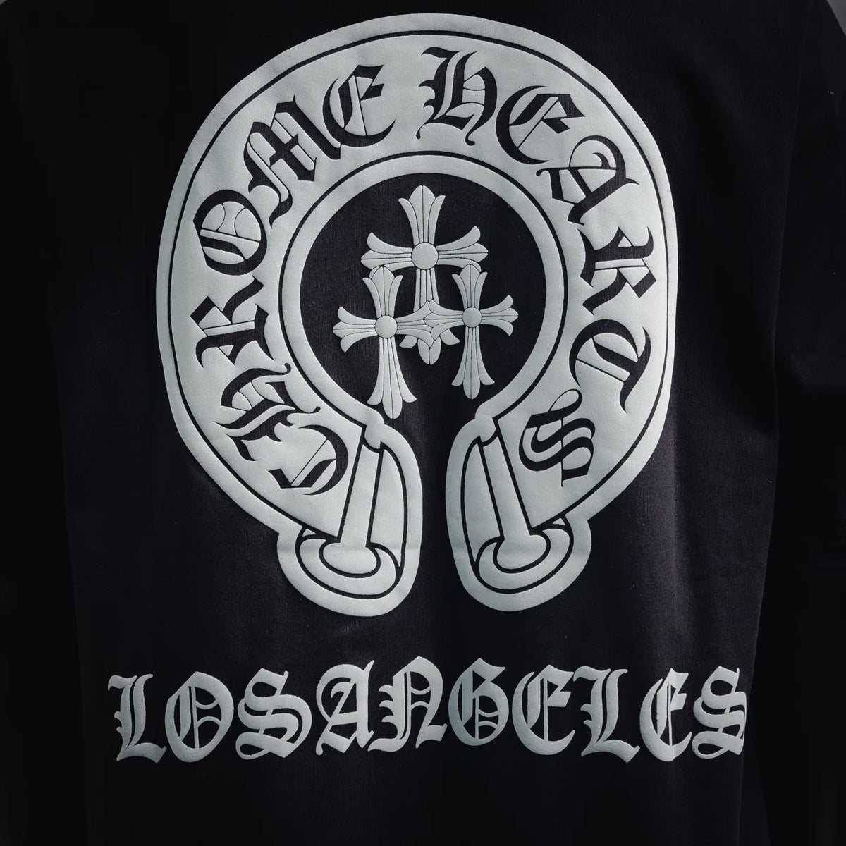Close-up of white crest emblem and raised-style lettering on the back of a black T-shirt