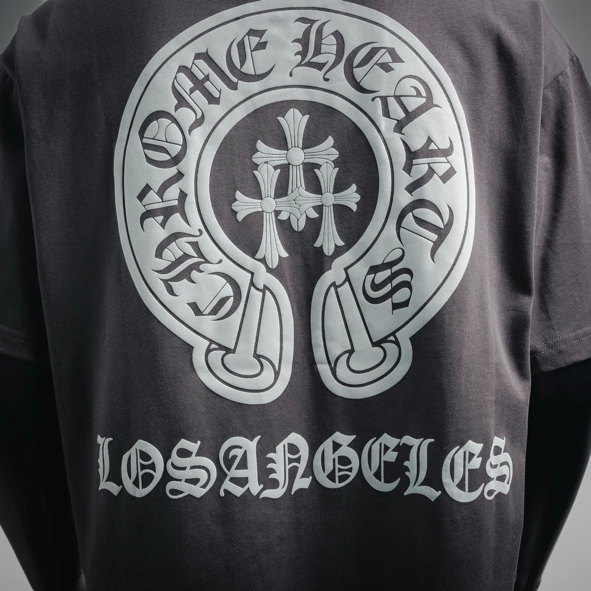 Charcoal T-shirt close-up of large white cross-like emblem and arc text