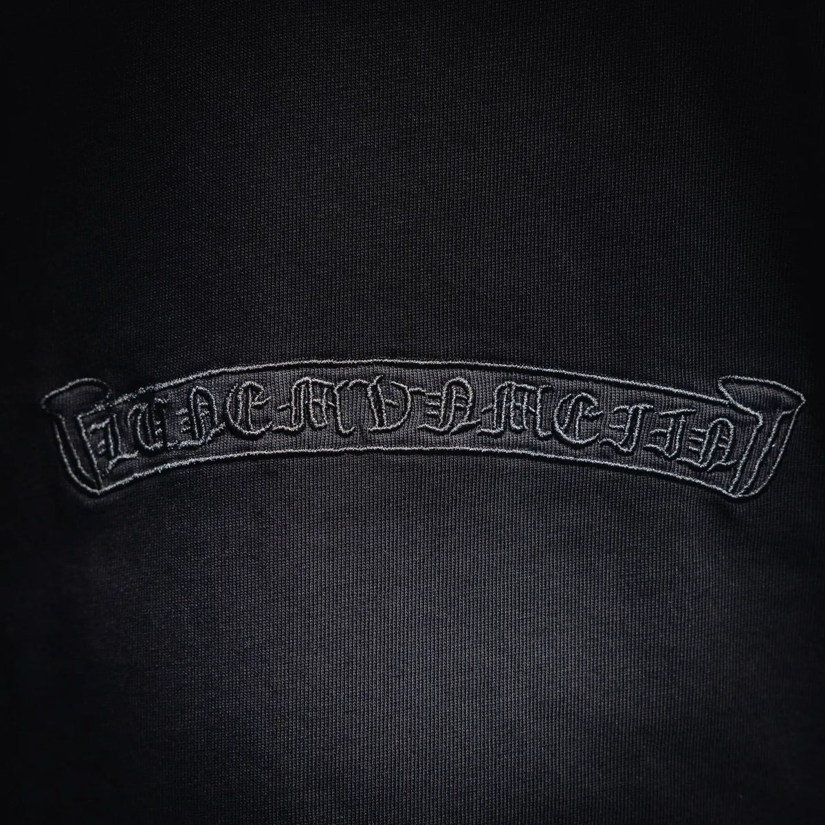 Black T-shirt neck patch with embroidered text on inner collar