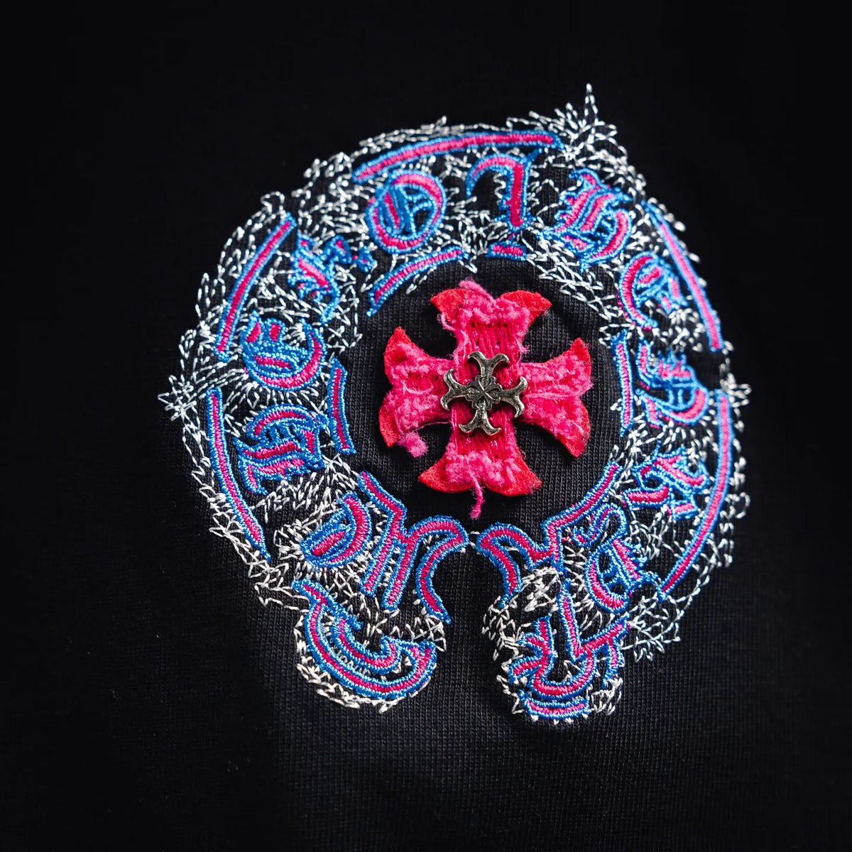 Close-up of black T-shirt back graphic: red cross emblem with ornate border stitching