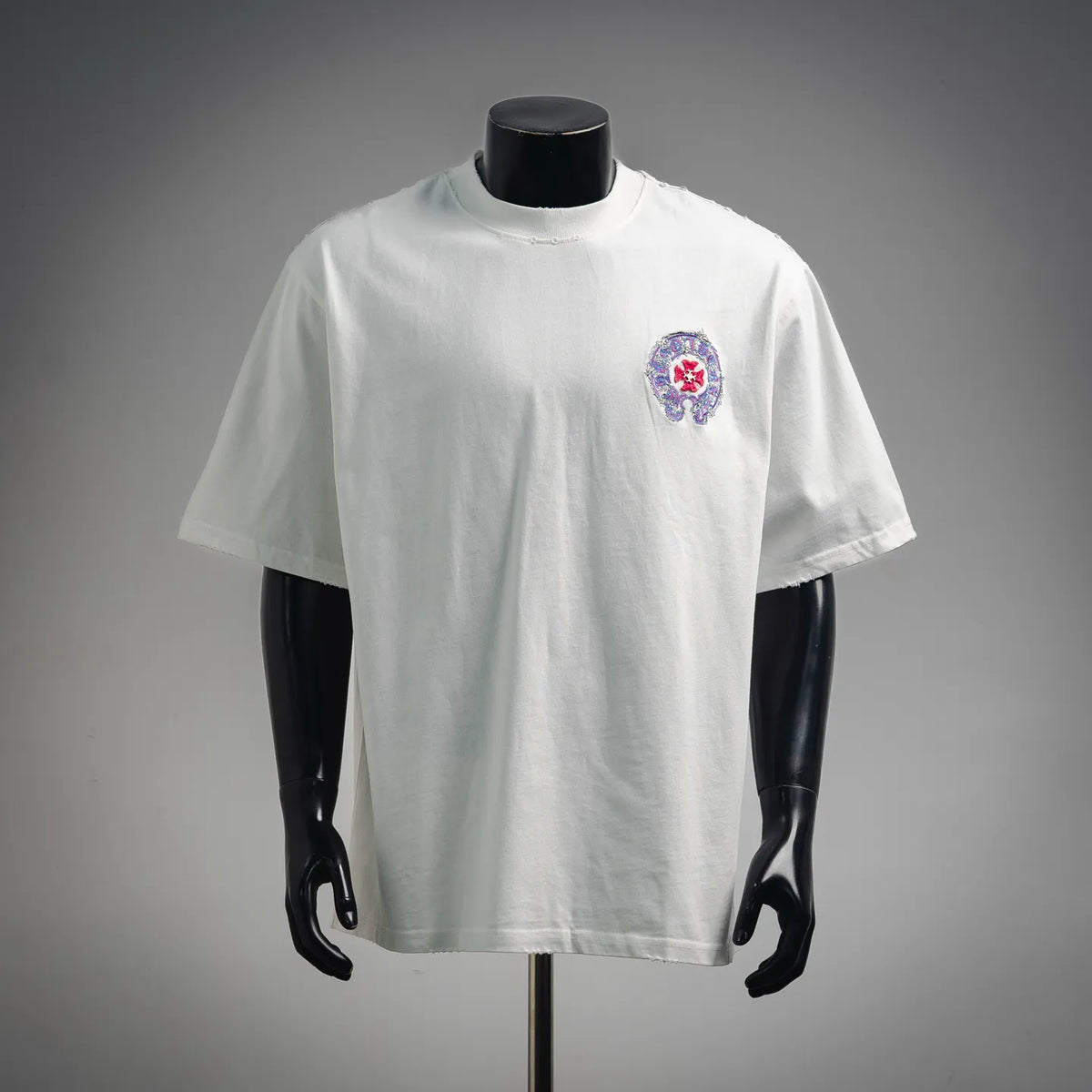 White short-sleeve T-shirt with small multicolor embroidered emblem on the chest.