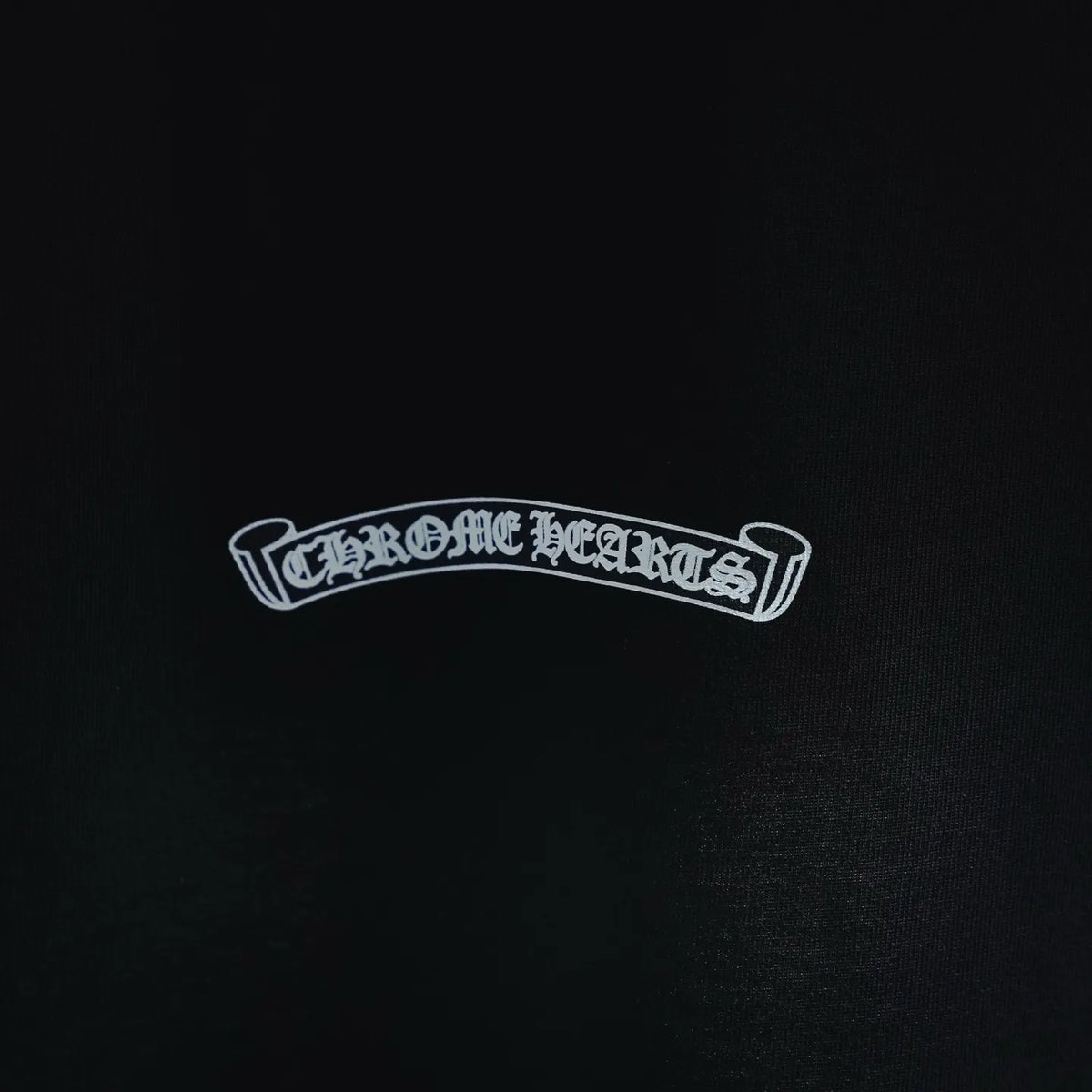 Black T-shirt chest emblem logo with white outlined banner-style text