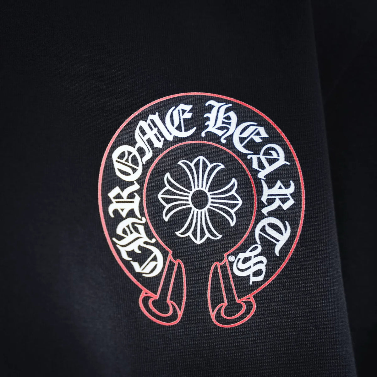 Front circular emblem on black T-shirt with red outline and white flower