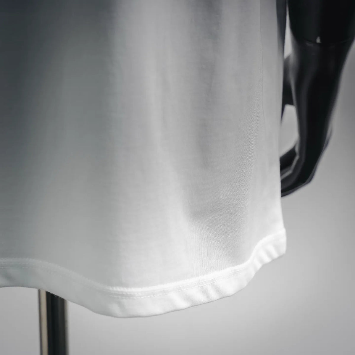White T-shirt hem close-up with smooth fabric and stitched bottom edge