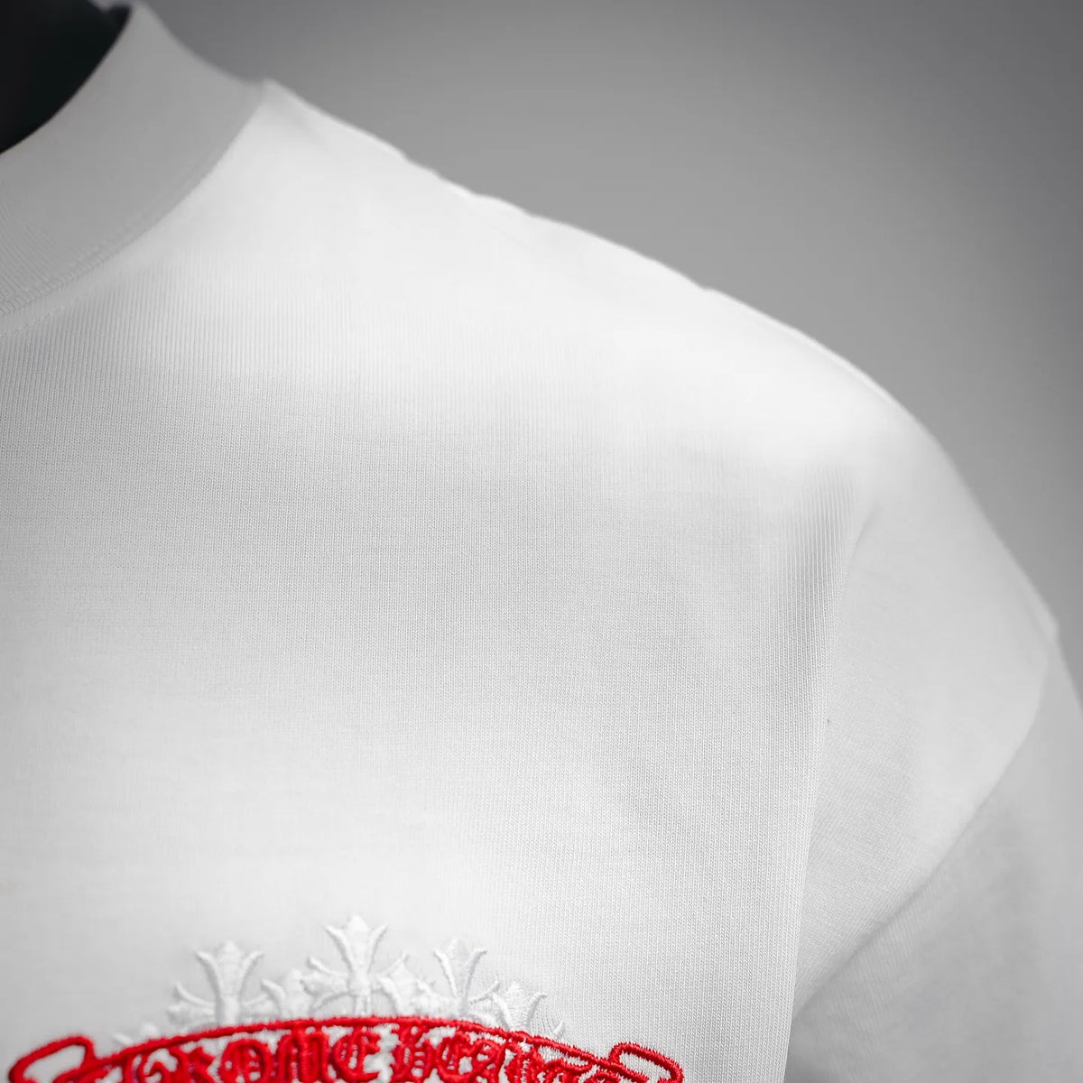 White T-shirt shoulder and upper sleeve with partial front logo embroidery