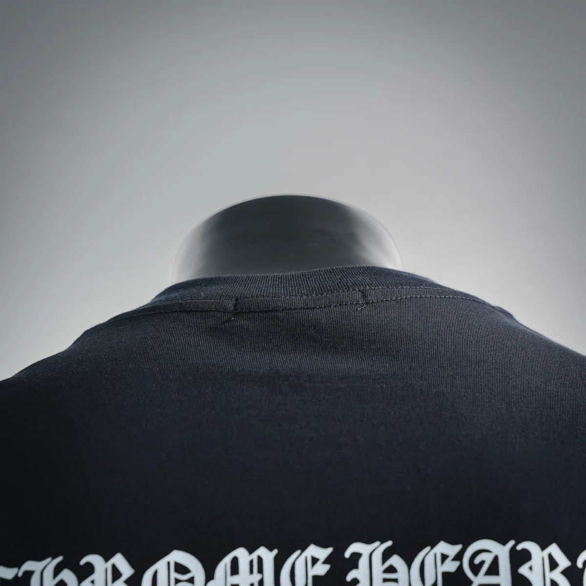 Back collar area of black T-shirt with partial white graphic print