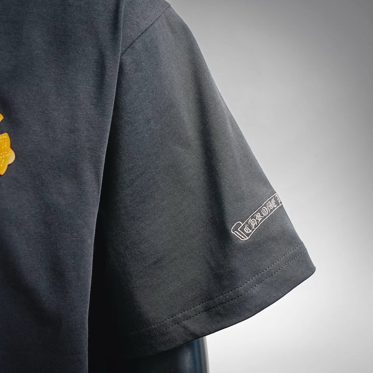 Dark T-shirt sleeve with small embroidered logo patch
