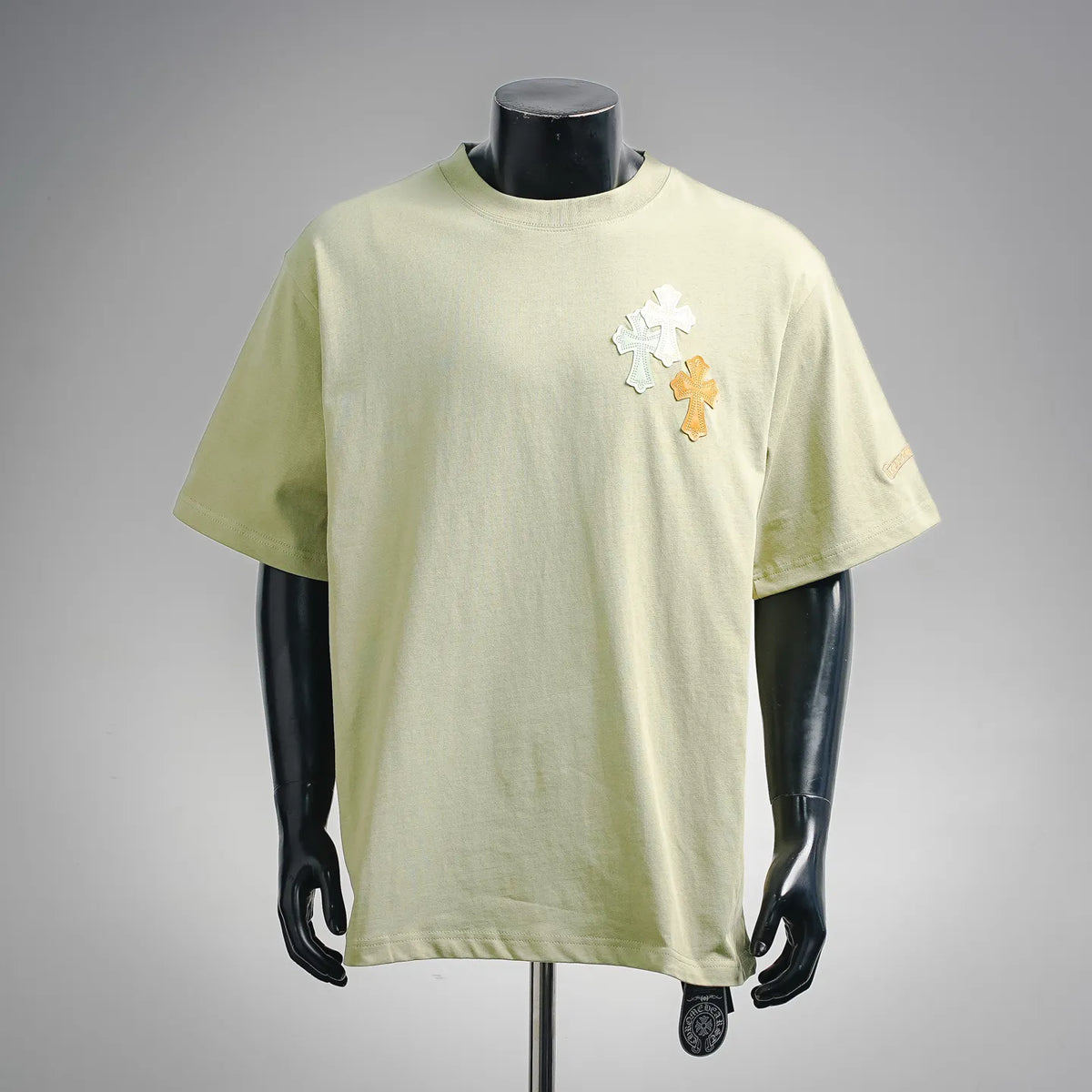 Light green short-sleeve T-shirt with multicolor cross patches on the front
