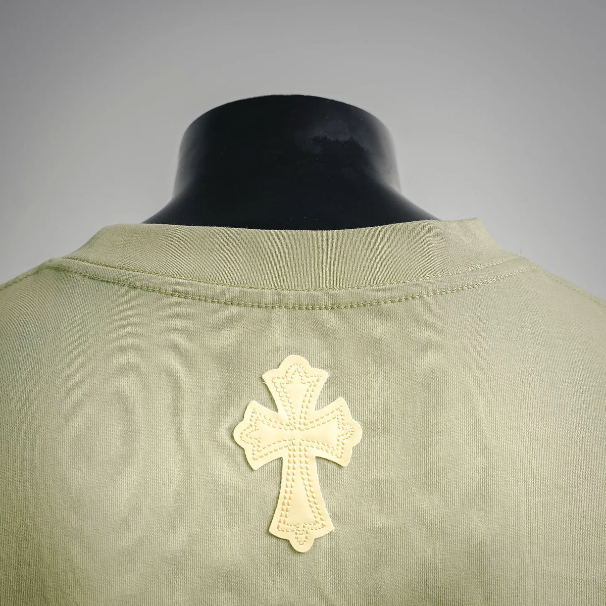 Light green T-shirt neckline with small white cross applique