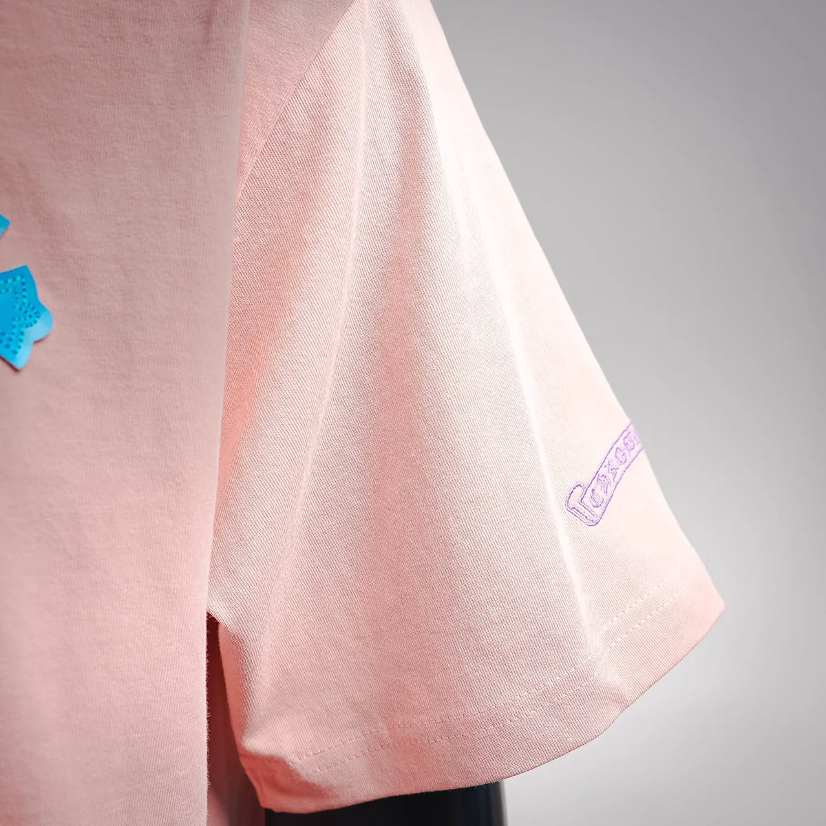 Pink short-sleeve T-shirt sleeve with small printed logo detail.