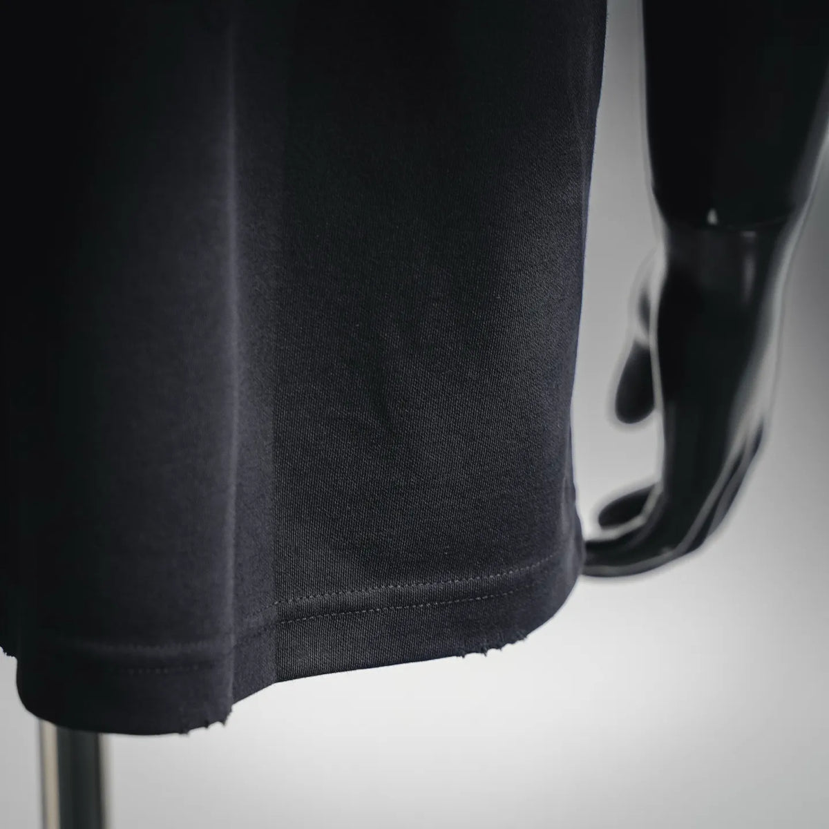 Black T-shirt fabric close-up with side seam detail and stitched lower edge