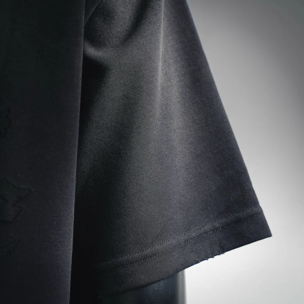Black T-shirt hem close-up with stitched edge and smooth fabric texture