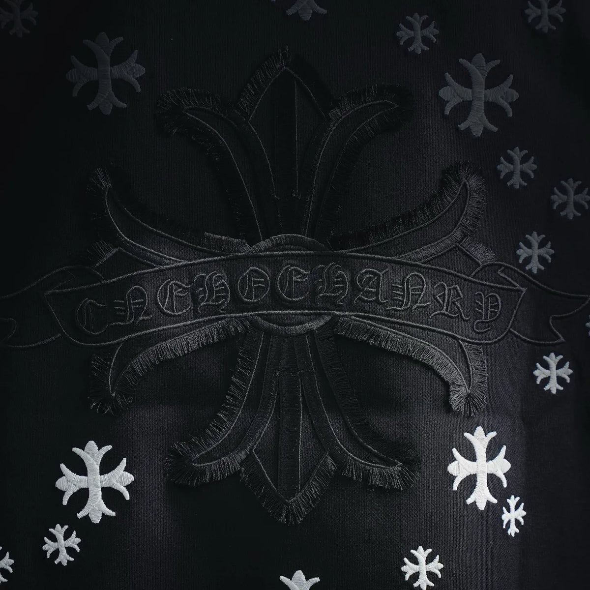 Close-up of black T-shirt back design: ornate center emblem with white snowflakes