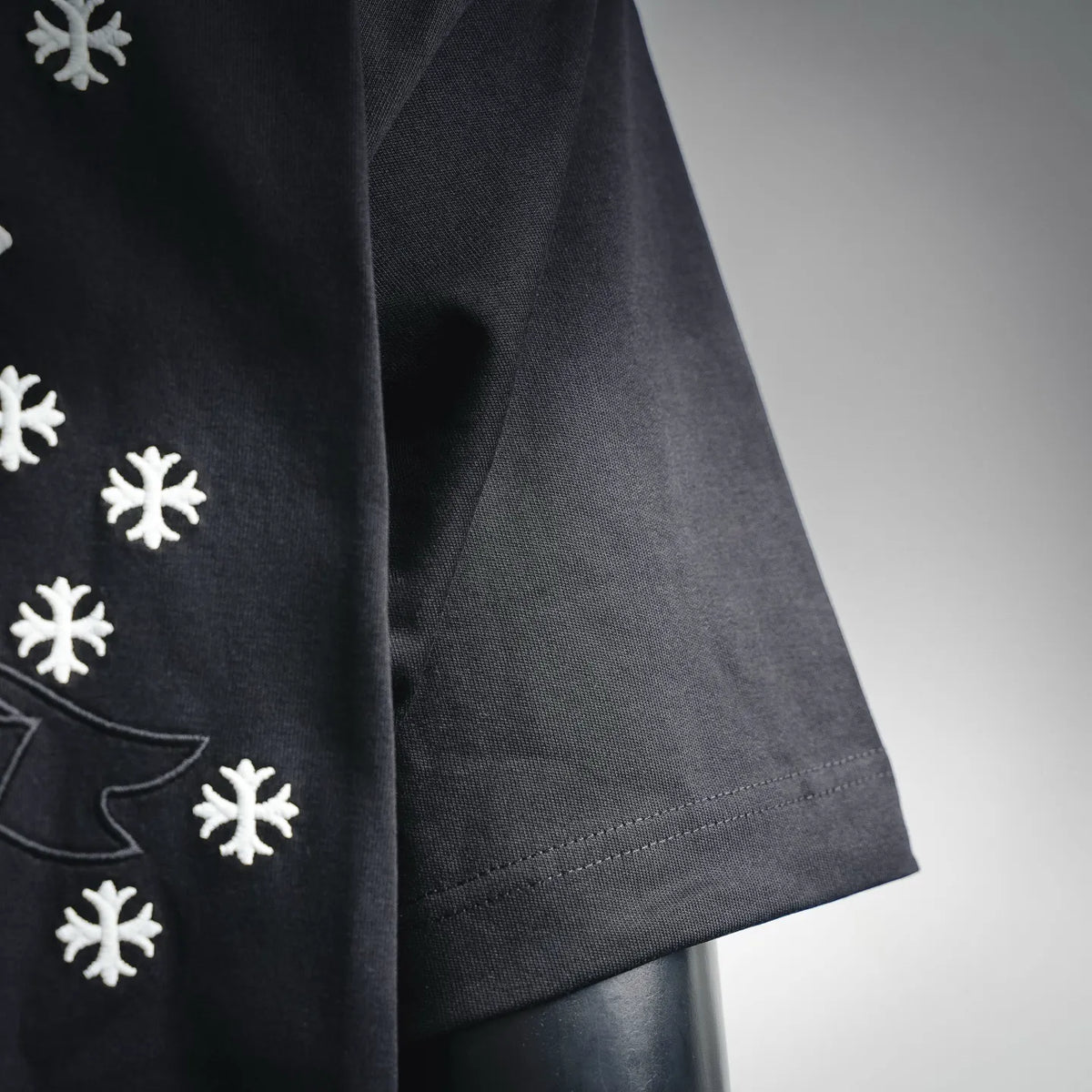 Black T-shirt side view with white snowflake prints near the lower seam