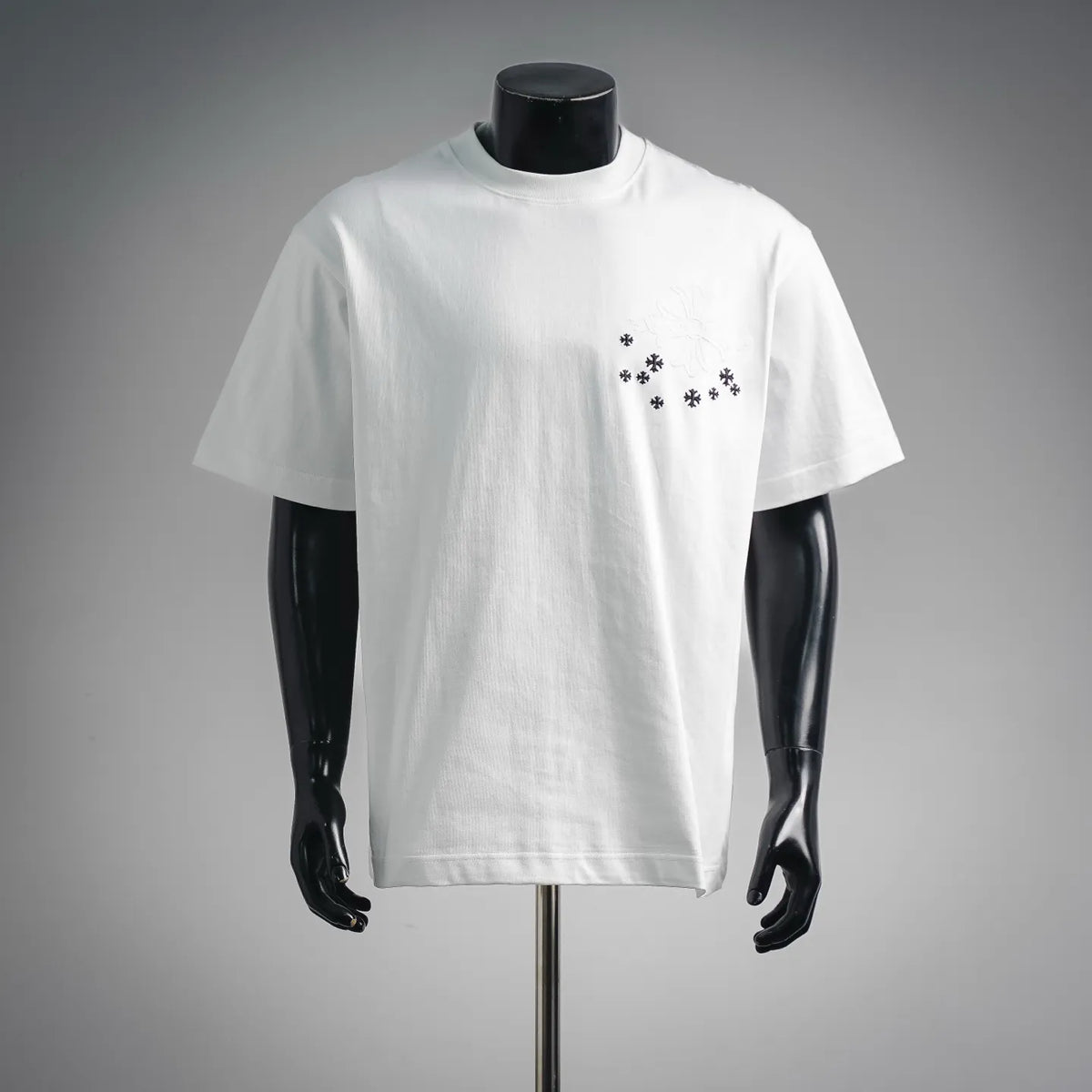 White short-sleeve T-shirt on mannequin with small black snowflake motifs on chest
