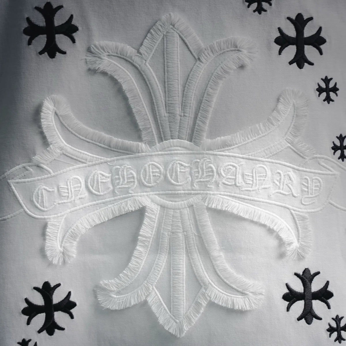 Close-up of white embroidered crest on T-shirt with black snowflake motifs around it