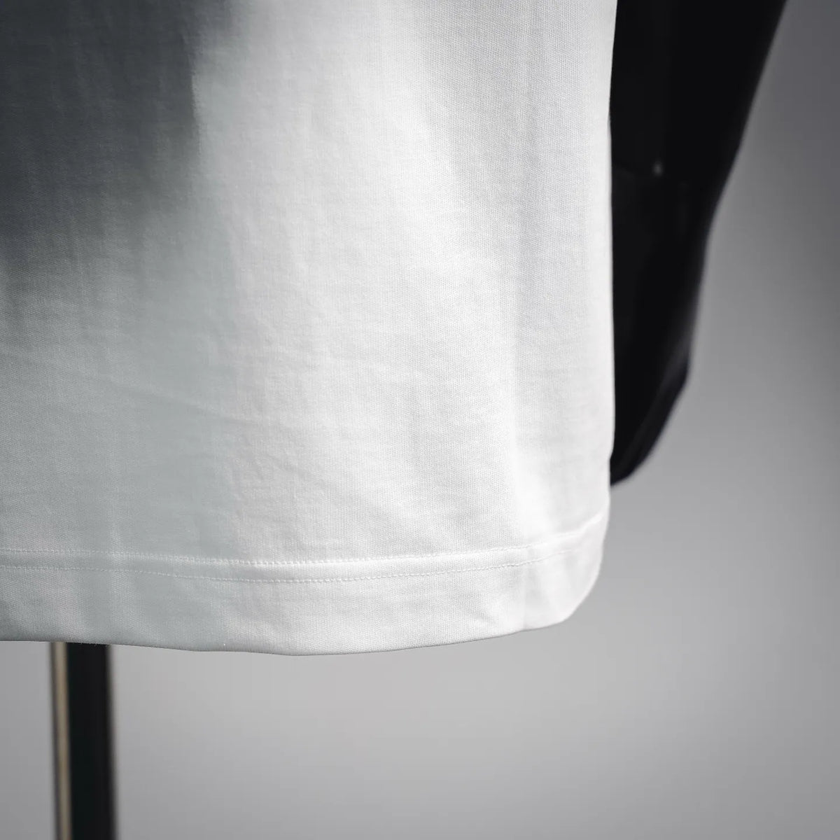 White short-sleeve T-shirt hem with visible stitching and clean lower edge