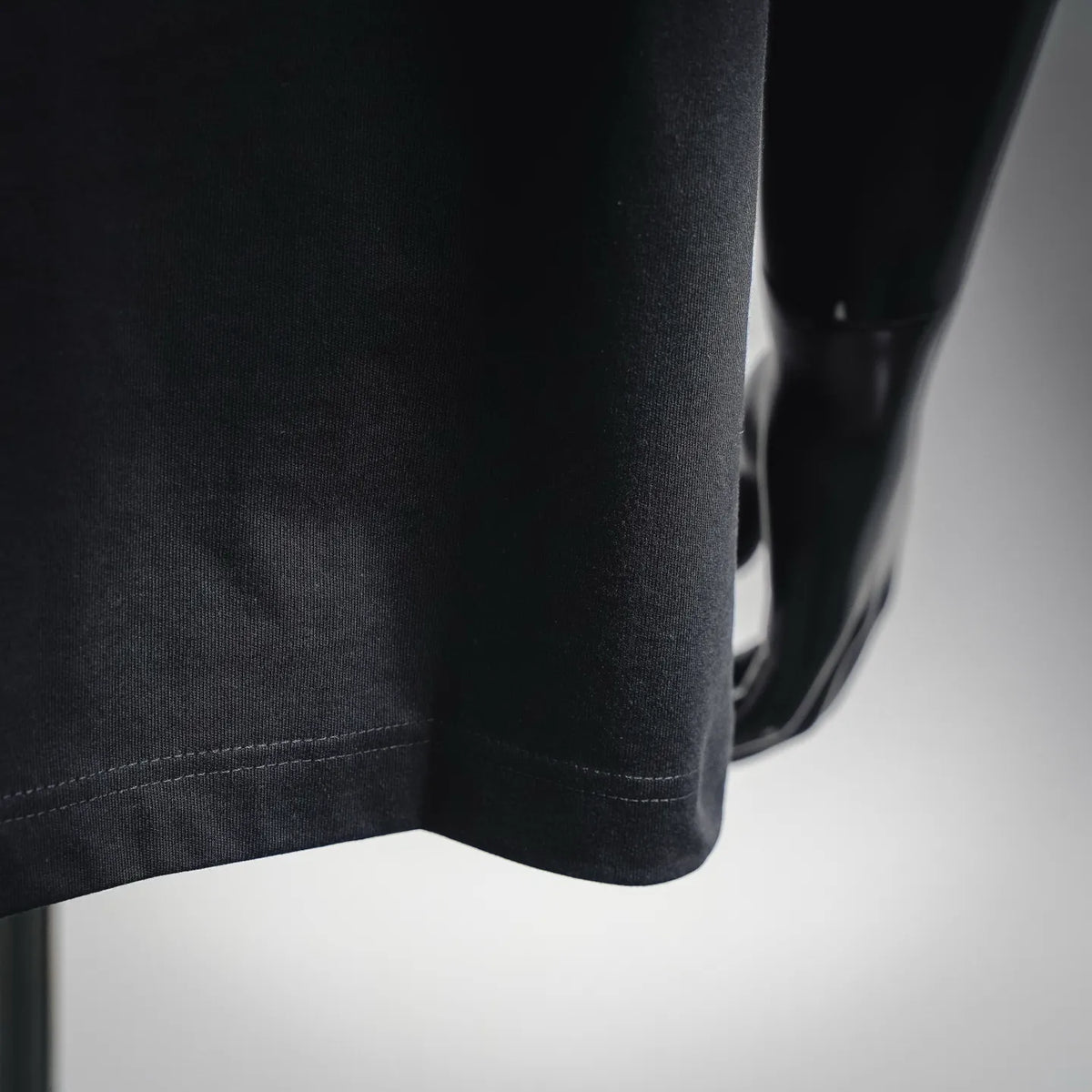 Black T-shirt fabric close-up showing side seam and curved hem.