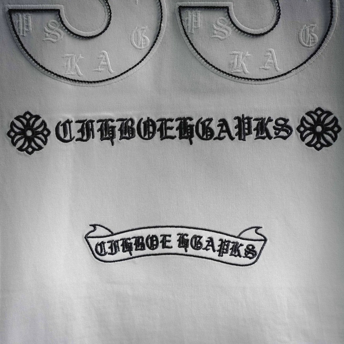 White T-shirt print detail: arched text and decorative elements beneath 33