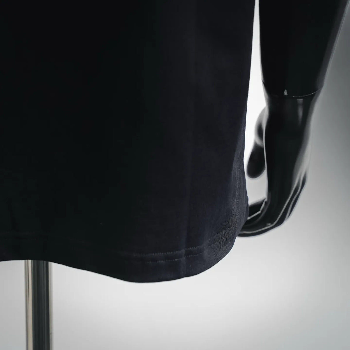 Black short-sleeve T-shirt hem and side view on a mannequin