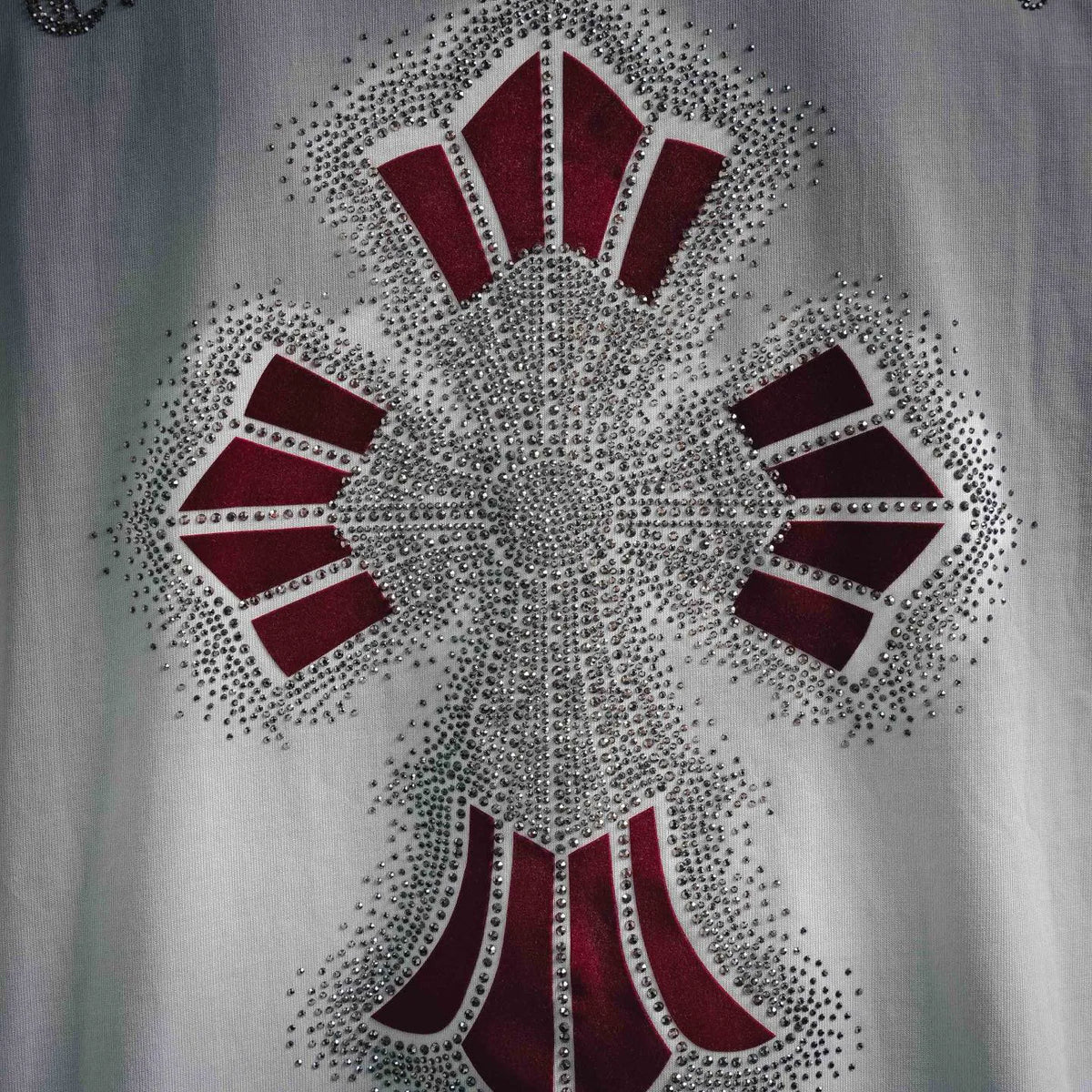 Close-up of rhinestone starburst graphic with dark and red sections on white tee