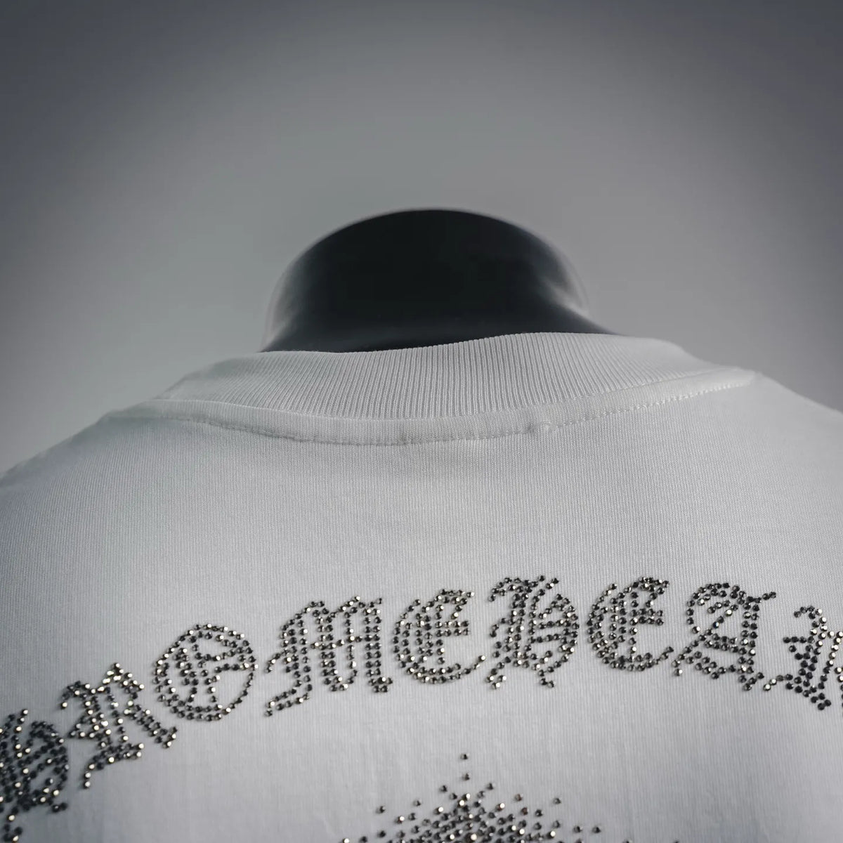 Ribbed crew neck of white T-shirt with rhinestone back lettering graphic close-up