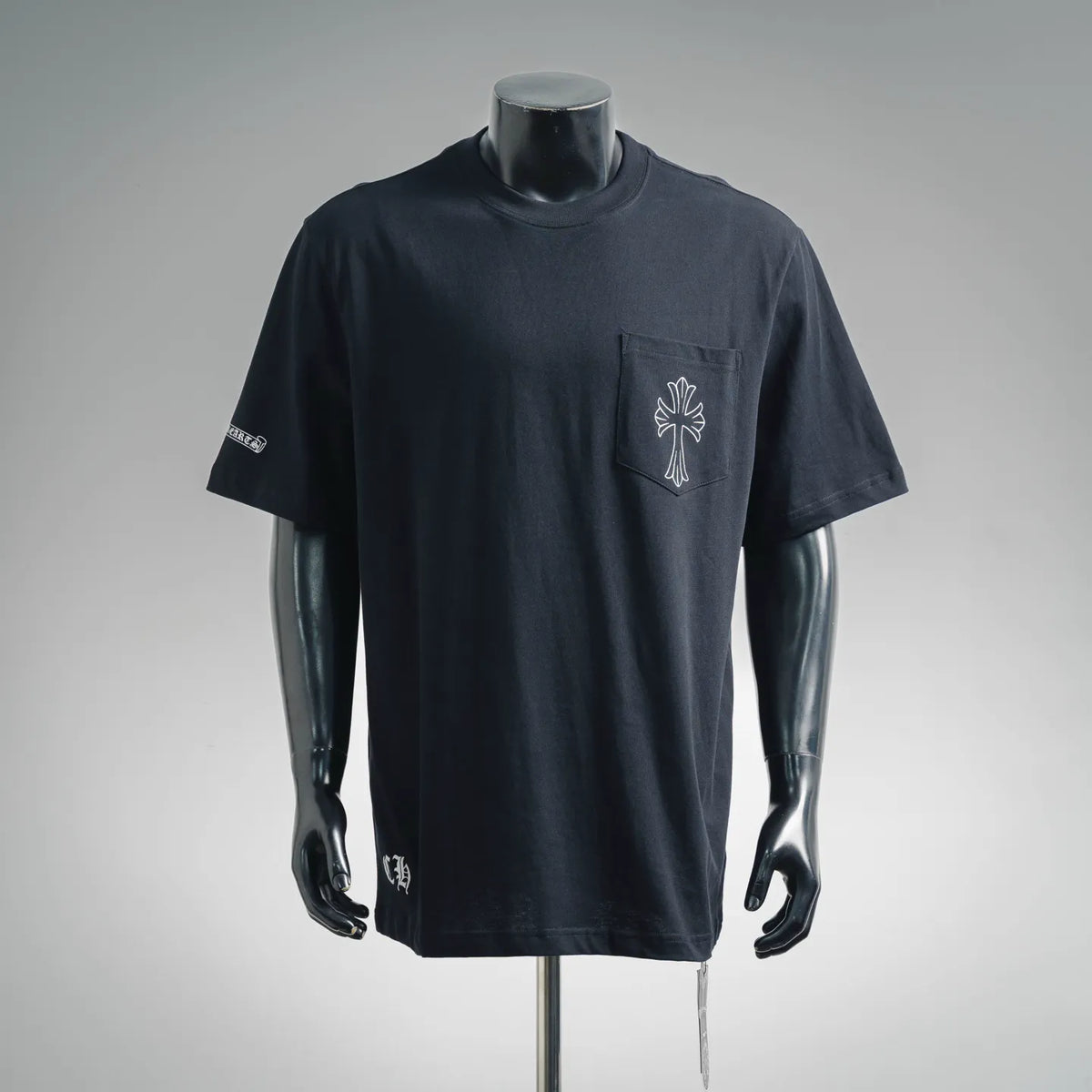 Black short-sleeve T-shirt with small white cross logo on chest and left sleeve patch