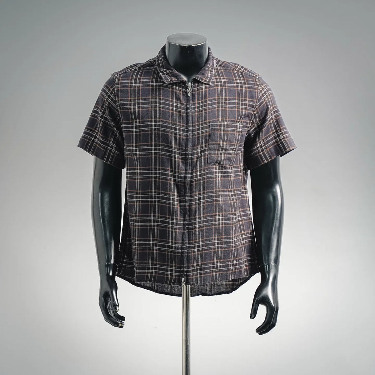 Plaid short-sleeve zip shirt on mannequin, dark base with tan and orange checks