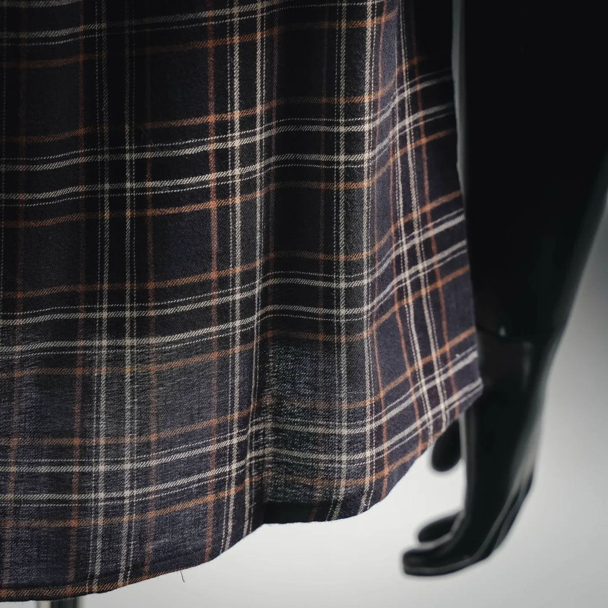 Plaid fabric close-up, dark knit with tan and orange intersecting lines