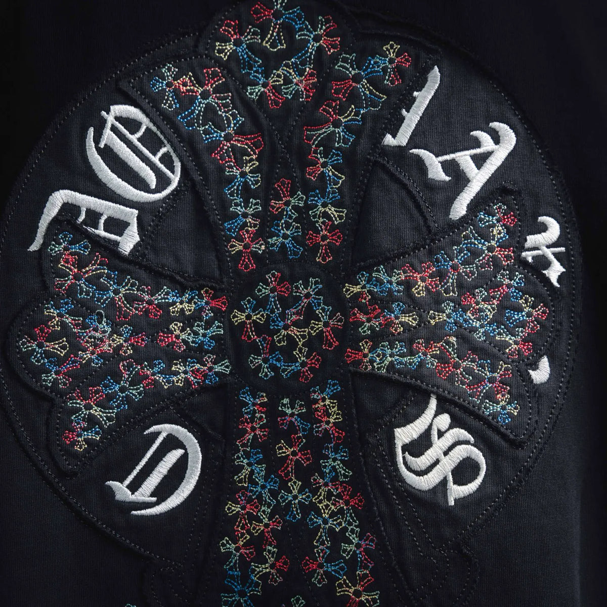 Embroidered cross design with colorful thread and white letters on black T-shirt